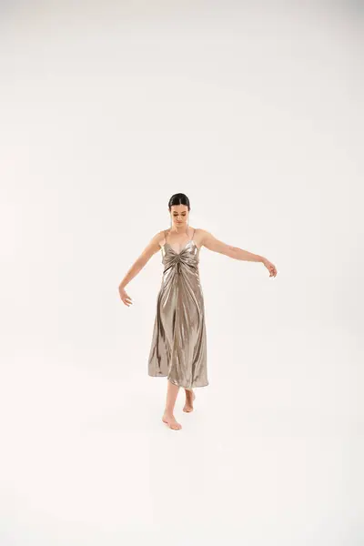 Une jeune femme danse élégamment dans une robe argentée fluide. — Photo de stock