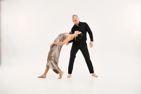 Un giovane uomo in nero e una giovane donna in un abito d'argento mostrano grazia ed elementi acrobatici in una posa da ballo. — Foto stock