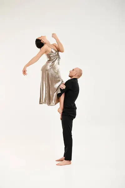 Un giovane uomo e una donna in abito argentato impegnati in una graziosa routine di danza, mostrando i loro movimenti sincronizzati e le loro abilità acrobatiche.. — Foto stock