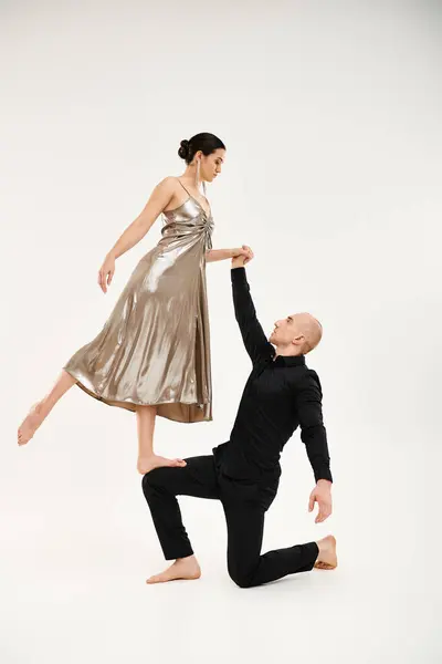 Ein junger Mann in Schwarz und eine junge Frau in einem Kleid tanzen anmutig zusammen und integrieren akrobatische Elemente. — Stockfoto