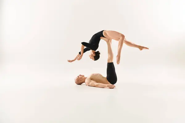 A shirtless young man and a woman showcasing acrobatic skills in a studio setting. — Stock Photo