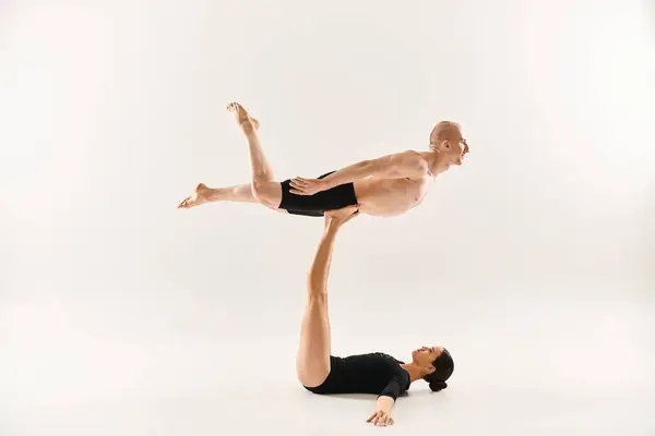 Jeune homme et femme torse nu en noir exécutant des éléments acrobatiques. — Photo de stock