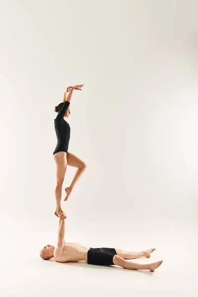 Um jovem sem camisa e uma mulher em uma pose de dança, mostrando sua flexibilidade fazendo divisões em um estúdio em um fundo branco. — Fotografia de Stock