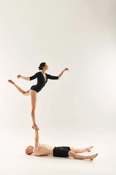 Jovem sem camisa e mulher dançando em um duo acrobático, desafiando a gravidade em um estúdio contra um pano de fundo branco. — Fotografia de Stock