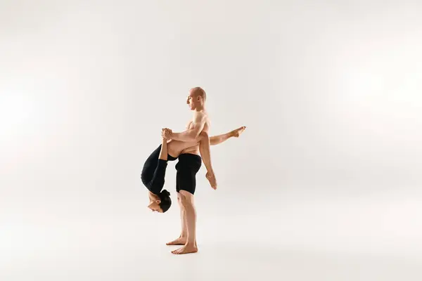 Un jeune homme torse nu et une femme dansent avec grâce acrobatique tout en flottant dans les airs sur un fond blanc. — Photo de stock
