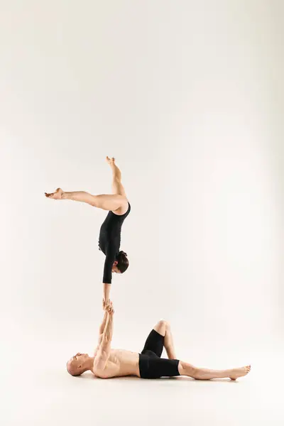 A shirtless young man and a woman gracefully perform a handstand in a studio setting on a white background. — Stock Photo
