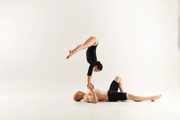 El hombre sin camisa equilibra en un handstand en otro hombre, mostrando fuerza y habilidad en acrobacias, fondo blanco del estudio. - foto de stock
