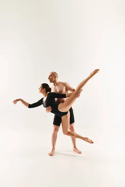Un joven sin camisa y una mujer bailan en el aire, ejecutando movimientos acrobáticos en un estudio sobre un fondo blanco. - foto de stock