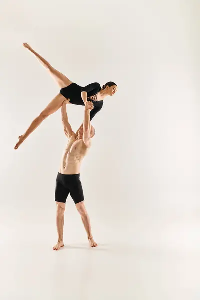 Un giovane uomo senza camicia e una donna si impegnano in una danza aggraziata e acrobatica sospesa a mezz'aria su uno sfondo bianco. — Foto stock