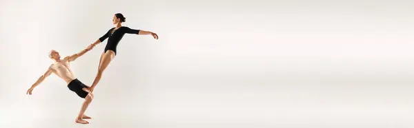 Un joven sin camisa y una mujer joven realizan elementos acrobáticos en el aire, mostrando una rutina de baile elegante y fascinante. - foto de stock