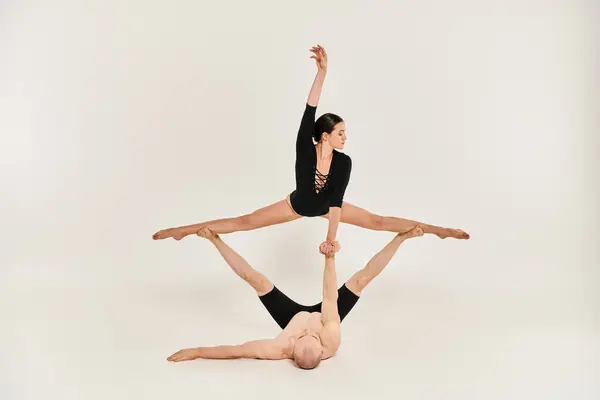 Ein hemdloser junger Mann und eine Frau führen anmutig akrobatische Bewegungen aus, während sie in der Luft in einem Studio-Setting schweben. — Stockfoto