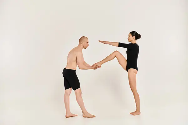 Un giovane uomo senza maglietta e una donna in nero eseguono mosse di danza acrobatica in un ambiente di studio. — Foto stock