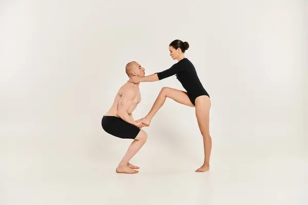 Un joven y una mujer sin camisa ejecutan movimientos acrobáticos de danza en un estudio sobre un fondo blanco. - foto de stock