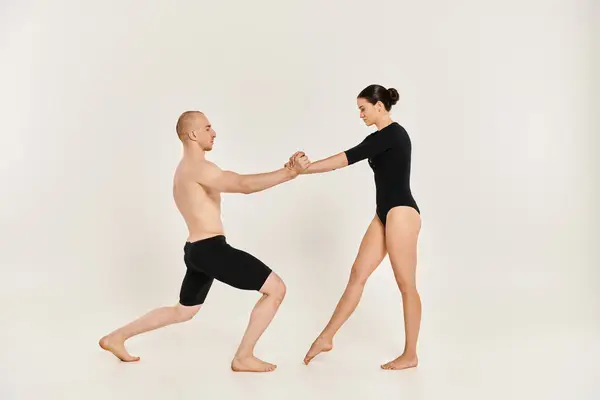Акробатичний молодий чоловік і жінка елегантно танцюють разом у студії, демонструючи свої граціозні рухи. — стокове фото