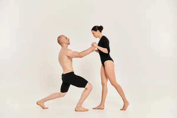 A shirtless young man and a woman performing intricate dance poses and acrobatic elements in a studio setting against a white background. — Stock Photo