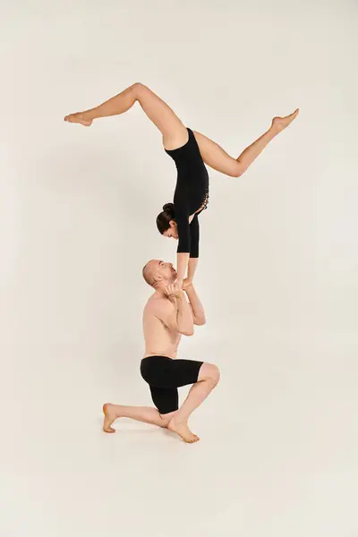 Молодий без сорочки чоловік і жінка виконують акробатичну мантію в повітрі, демонструючи свої танцювальні таланти на білому тлі. — стокове фото