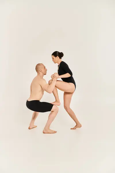 A shirtless young man and a woman in a couple performing acrobatic dance moves in a studio setting on a white background. — Stock Photo