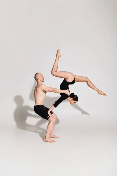 Мужчина и женщина без рубашки выполняют синхронную стойку на руках в захватывающем акробатическом дисплее на белом фоне. — стоковое фото