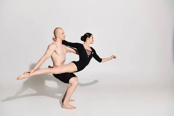 Un giovane uomo a torso nudo e una giovane donna eseguono movimenti acrobatici di danza in uno studio ambientato su uno sfondo bianco. — Foto stock