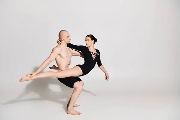 Un giovane uomo senza maglietta e una donna in una coppia che si esibiscono in una danza aggraziata e acrobatica si muovono in uno studio ambientato su uno sfondo bianco. — Foto stock