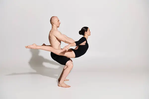 Un jeune homme torse nu et une femme dansent ensemble, exécutant des mouvements acrobatiques avec élégance et agilité sur fond de studio blanc. — Photo de stock