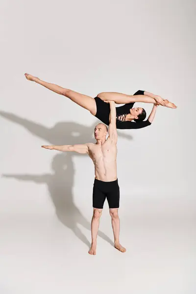 Un joven sin camisa y una mujer bailan acrobáticamente en un estudio sobre un fondo blanco. - foto de stock