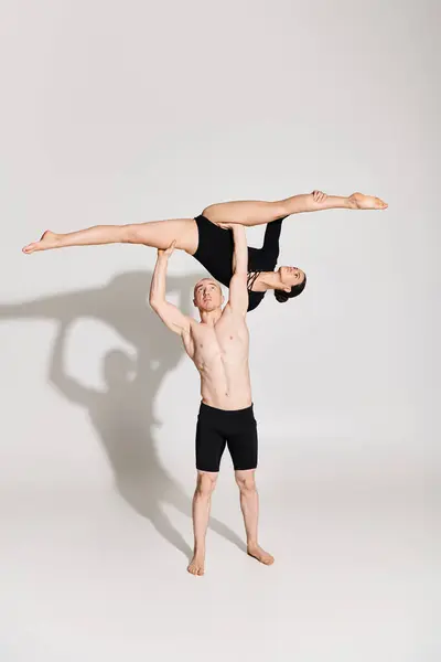 Hombre y mujer jóvenes sin camisa participan en acrobacias de soporte de mano sincronizadas, mostrando equilibrio y fuerza. - foto de stock
