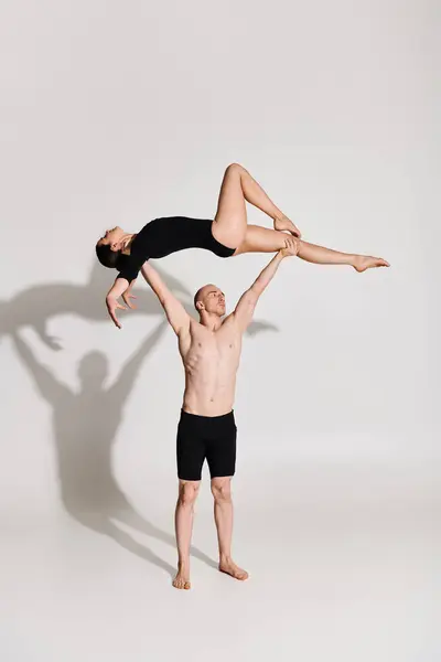 Ein hemdloser junger Mann und eine Frau führen vor weißem Hintergrund akrobatische Tanzbewegungen in der Luft vor. — Stockfoto