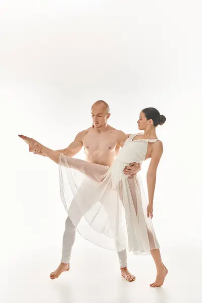 Un giovane uomo a torso nudo e una donna in abito bianco eseguono acrobatiche mosse di danza in questo studio girato su uno sfondo bianco. — Foto stock