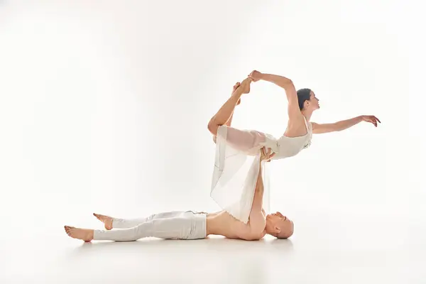 A shirtless young man and a woman in a white dress showcase their acrobatic dance moves in perfect sync against a white background. — Stock Photo