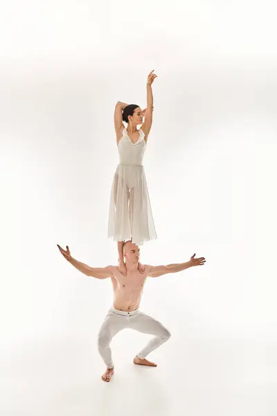 Shirtless young man and woman in white dress display acrobatic dance moves, studio shot. — Stock Photo