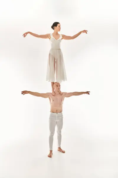 Jovem sem camisa e mulher de vestido branco mostram talento acrobático, equilibrando em uma pose de dança dinâmica. — Fotografia de Stock