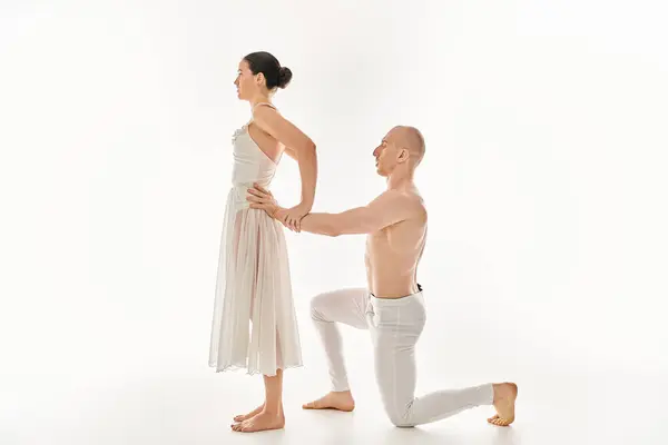 Un giovane uomo, senza maglietta, e una giovane donna in abito bianco che esegue elementi acrobatici in una graziosa routine di danza. — Foto stock