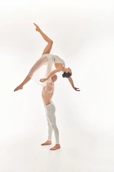 Jovem sem camisa homem e mulher de vestido branco realizar dança acrobática no ar, desafiando a gravidade em estúdio. — Fotografia de Stock