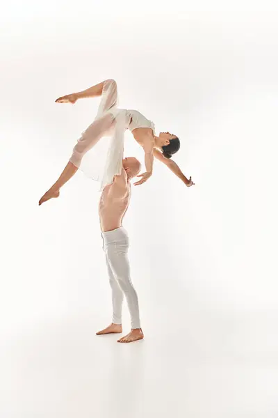A shirtless young man and a woman in a white dress showcasing their acrobatic skills. — Stock Photo