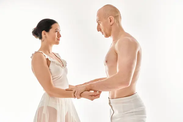 Un giovane uomo a torso nudo e una donna in abito bianco si esibiscono insieme in uno studio di danza su uno sfondo bianco. — Foto stock