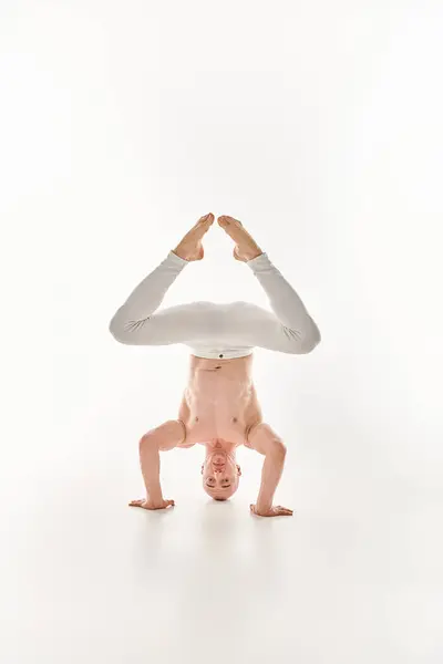 Молодой человек демонстрирует свои акробатические навыки, выполняя стойку на голове, захваченную в студии на белом фоне. — стоковое фото