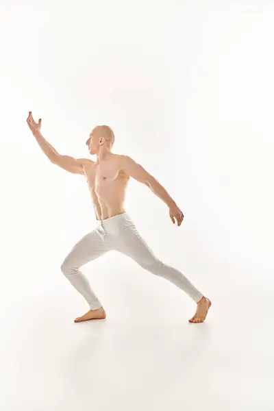 Молодий чоловік, без сорочки, демонструє акробатичні навички під час танців у студії на білому тлі. — стокове фото