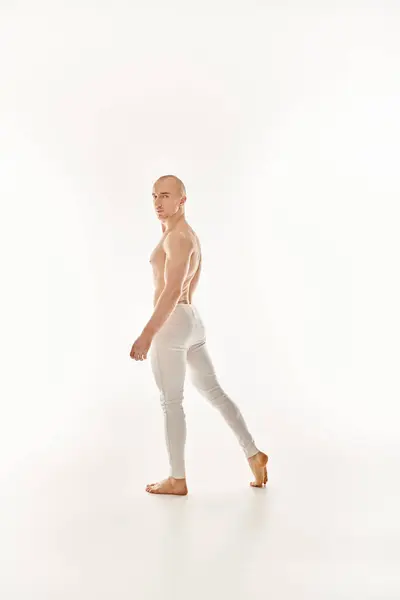Un giovane senza maglietta mette in mostra le sue abilità acrobatiche attraverso la danza su uno sfondo bianco. — Foto stock