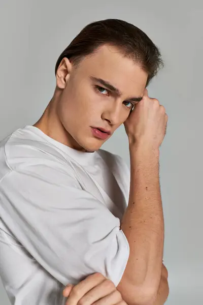 Good looking debonair young man in elegant stylish t shirt looking at camera on gray background — Stock Photo