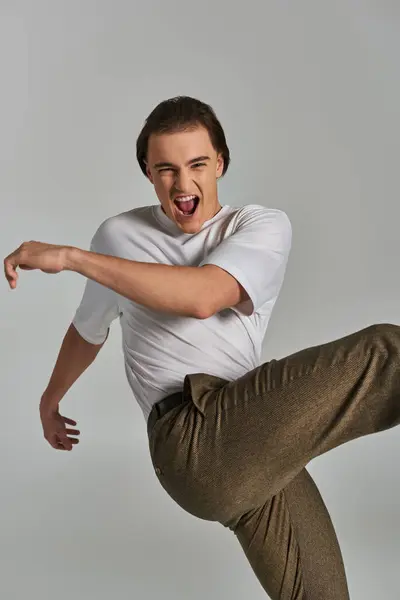Good looking joyous man in elegant attire posing in motion on gray background, fashion concept — Stock Photo