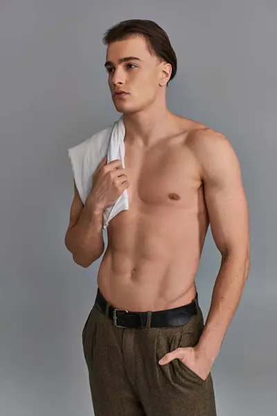 Alluring attractive young man in brown pants posing topless on gray background and looking away — Stock Photo