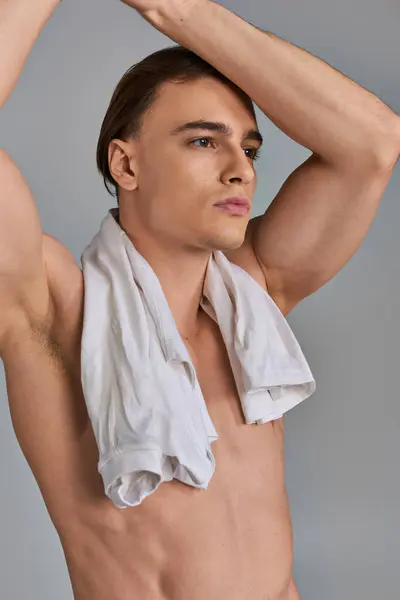 Alluring handsome young man in brown pants posing topless on gray background and looking away — Stock Photo