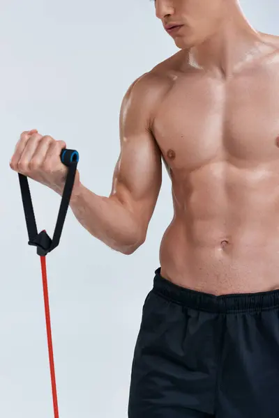 Vista recortada de un joven atlético sin camisa de entrenamiento con expansor de fitness sobre fondo gris - foto de stock