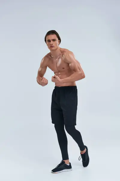 Attractive sexy shirtless man in black sporty pants posing alluringly and looking at camera — Stock Photo