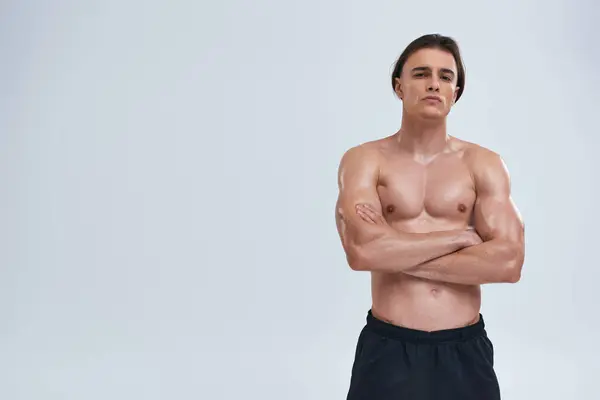 Good looking sexy shirtless man in black sporty pants posing alluringly and looking at camera — Stock Photo