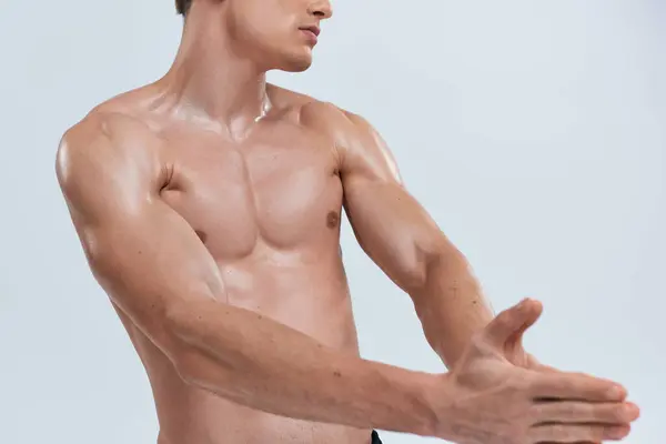 Recortado vista de hombre atlético posando en topless sobre fondo gris y jugando sus músculos en la cámara - foto de stock