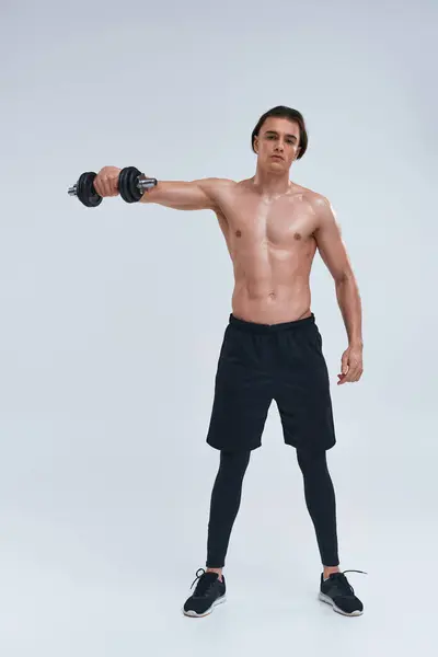 Attrayant homme athlétique posant seins nus exercice activement avec haltère et en regardant la caméra — Photo de stock