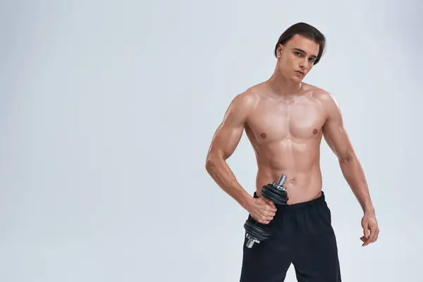 Attrayant homme athlétique posant seins nus exercice activement avec haltère et en regardant la caméra — Photo de stock