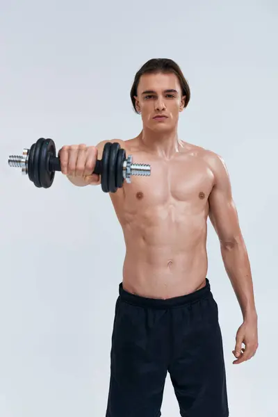 Atractivo atlético hombre posando en topless ejercicio activamente con la mancuerna y mirando a la cámara - foto de stock